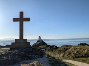 The ruins of St Dwynwen's Church and lighthouse on Ynys Llanddwyn, Anglesey, with the Eryri mountains visible across the water