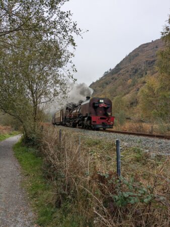 Steam train passes Fisherman's walk footpath in Beddgelert
